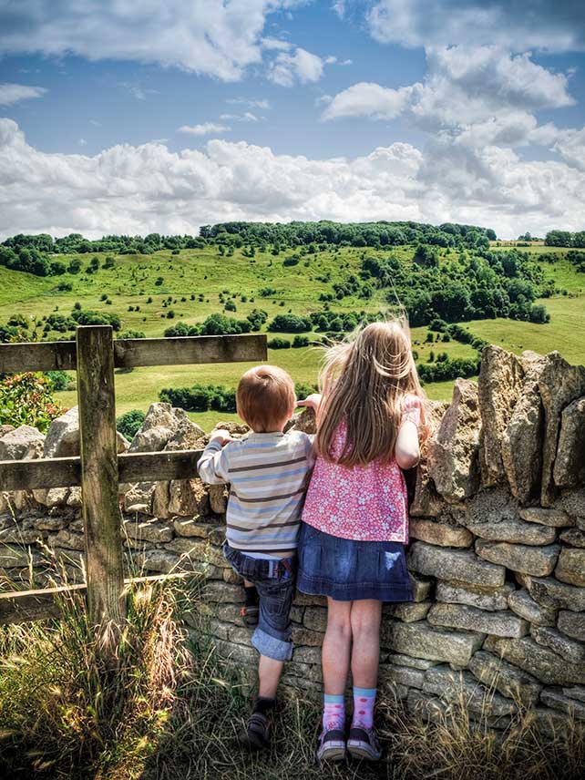 Children looking over country wall, Cotswolds, Gloucestershire UK. ©fotoMonkee.