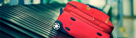 Red suitcase on conveyor belt.