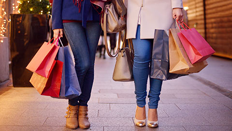 Two women walking down a street with shopping bags.