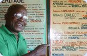 Homme de Tobagan devant des panneaux d'information.