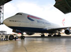 A Boeing 747 taxis into an aircraft hanger.