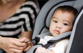 An infant strapped into a car seat.