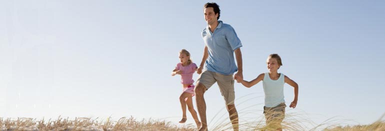 Padre e hijos sobre dunas de arena.