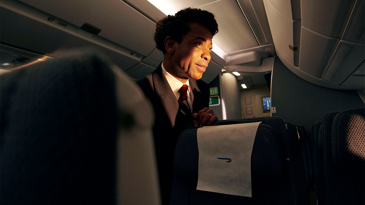 Male cabin crew onboard looking out with warm lighting touching his face.