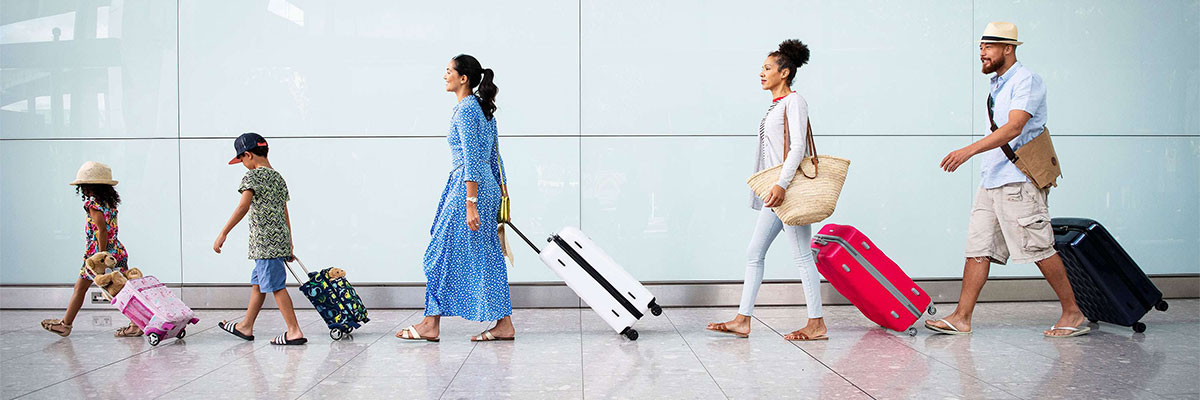 런던 히드로 공항 5 번 터미널에서 여행 가방을 들고 걷고 있는 가족.