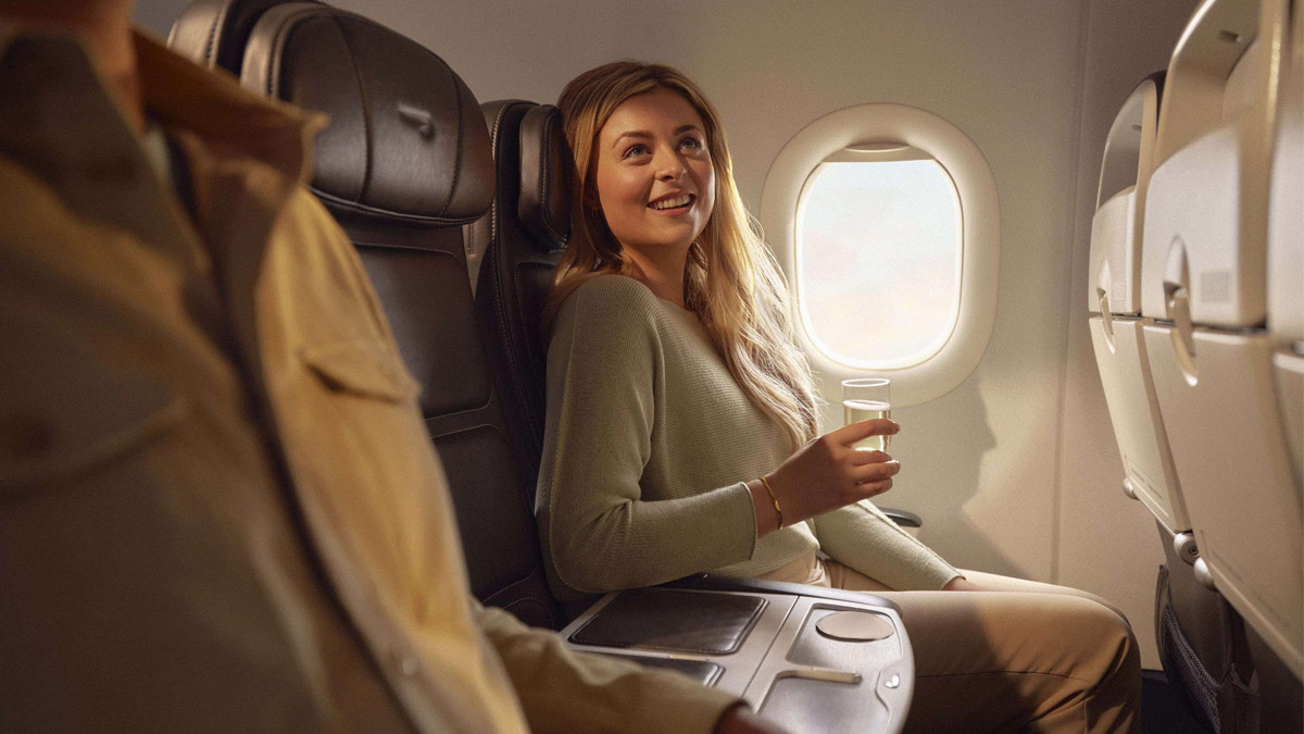Ein weiblicher Fluggast auf einem Club Europe-Fensterplatz mit einem Getränk.