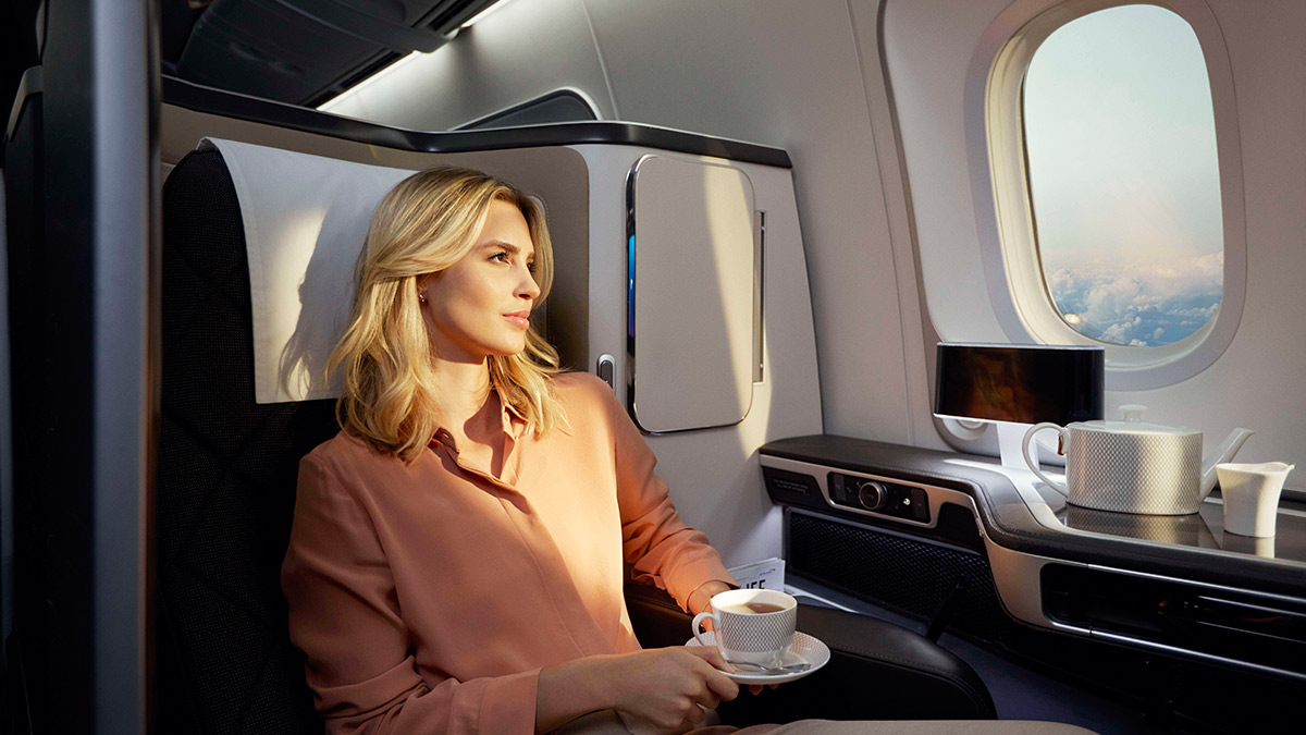 头等客舱 (First) 中的一位女士一边喝茶，一边凝视着窗外。