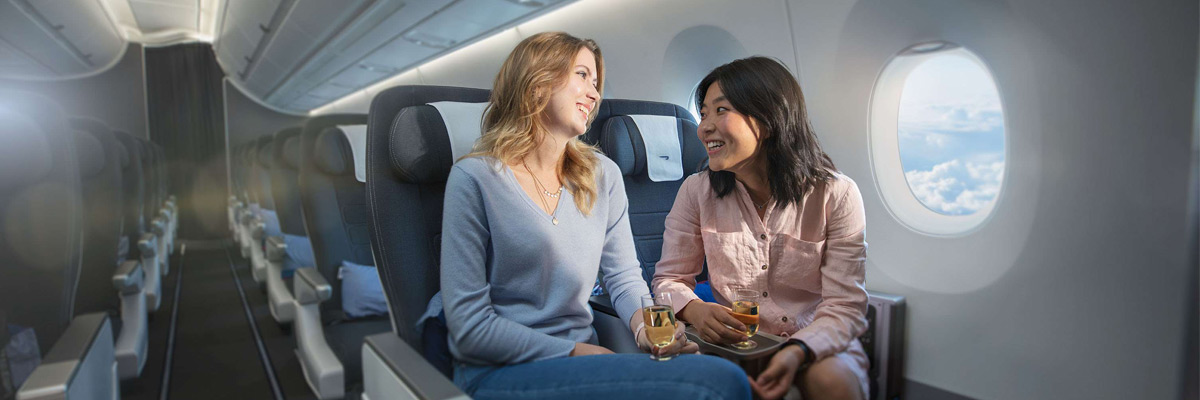 两位坐在飞机上面带笑容的女孩。