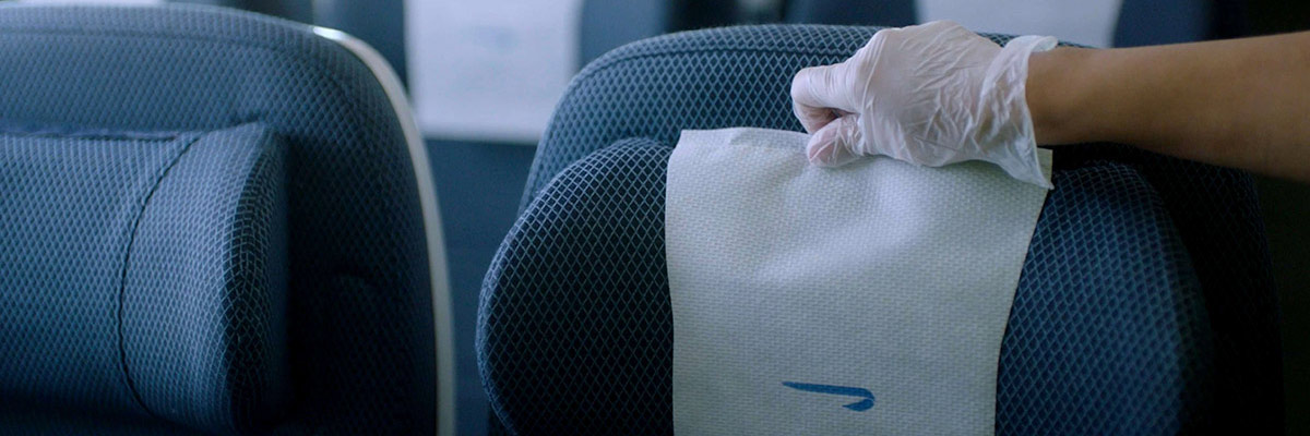 英国航空 (British Airways) 清洁团队正在经济客舱 (World Traveller) 中更换椅套的特写。