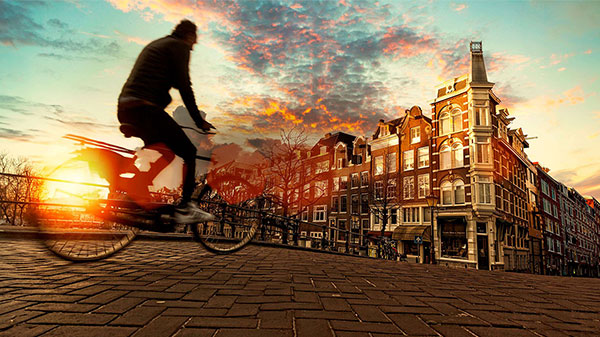 A bike rider at sunset on the streets on Amsterdam.