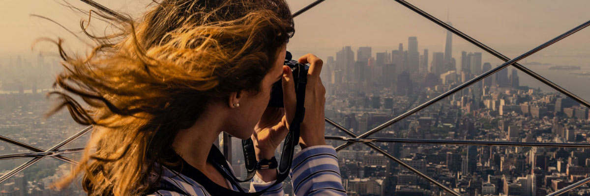 Woman taking photographs from a look out point over New York city, USA.
