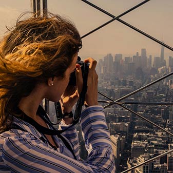 Woman taking photographs from a look out point over New York city, USA
