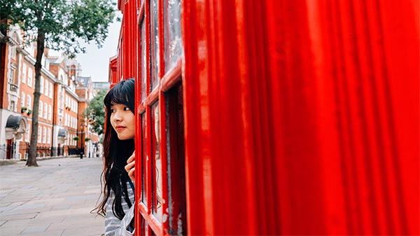 Girl leaning out phone booth in London.