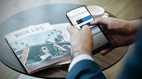 Hombre utilizando smartphone con el sitio web de On Business en la pantalla.