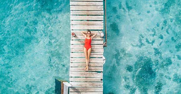 Aerial shot of womnn relaxing in a water bungalow.