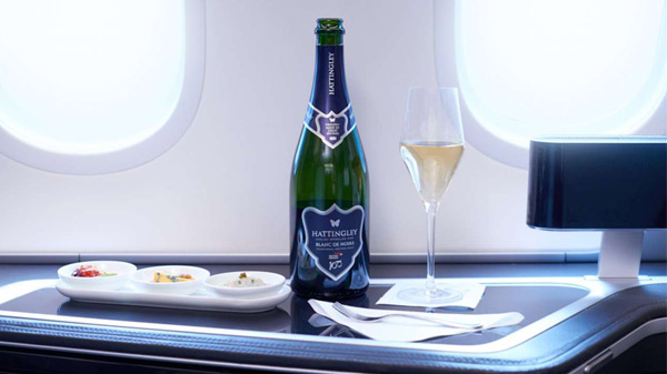 Botella de champán Hattingley Valley y aperitivos dentro de un avión.