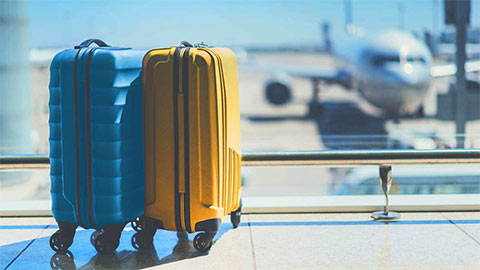One blue and one yellow trolley suitcases at the terminal