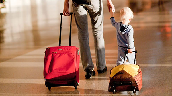 Donna e bambino che trasportano valigie.