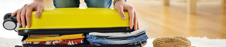 Lady packing clothes into travel bag.