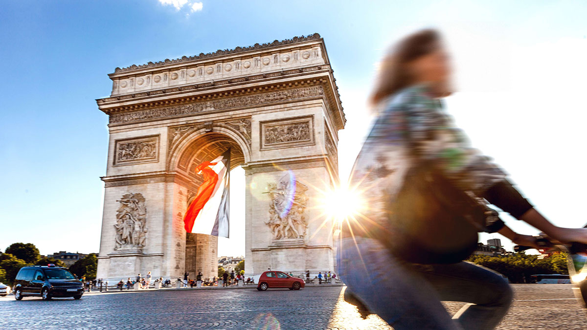Arc de Triomphe in Paris with a big French flag under it.