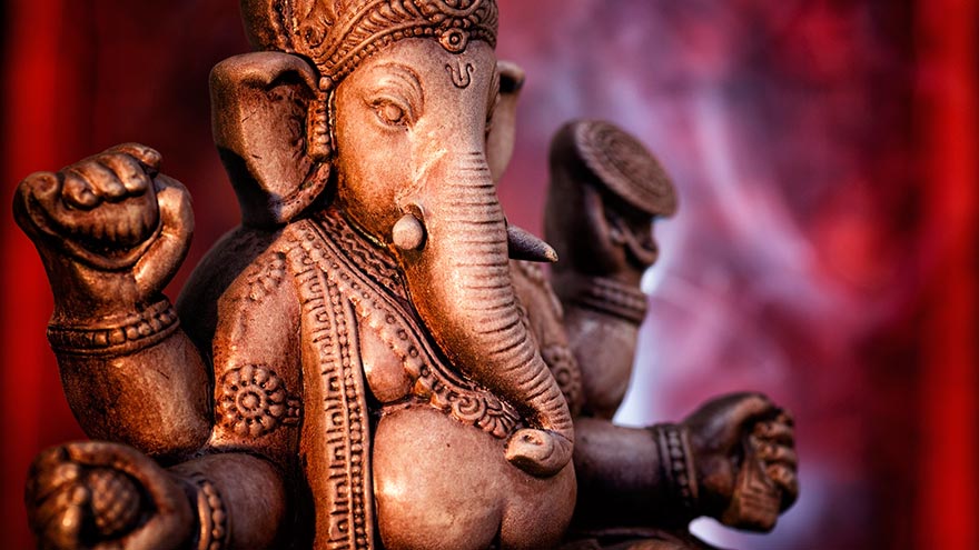 Una statua di Ganesha, una divinità dell'India, su uno sfondo rosso.