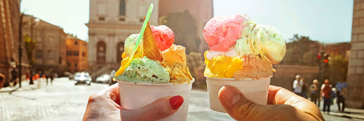 Couple with beautiful bright sweet Italian ice-cream with different flavors in the hands on the square in Rome, Italy.