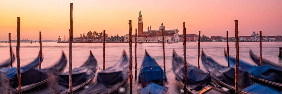 Scenic view of gondolas and San Giorgio Maggiore basilica in Venice at colorful sunrise, Italy.