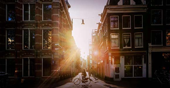 A person cycles through inner-city Amsterdam in the early morning.