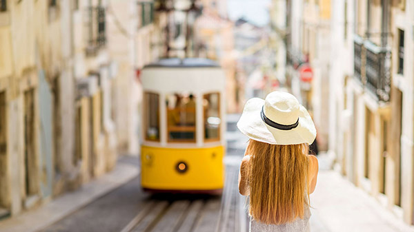 Woman standing behind tram in Lisbon, Portugal.