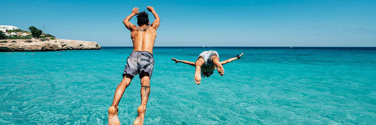 Two people jumping into the sea in Palma, Mallorca.