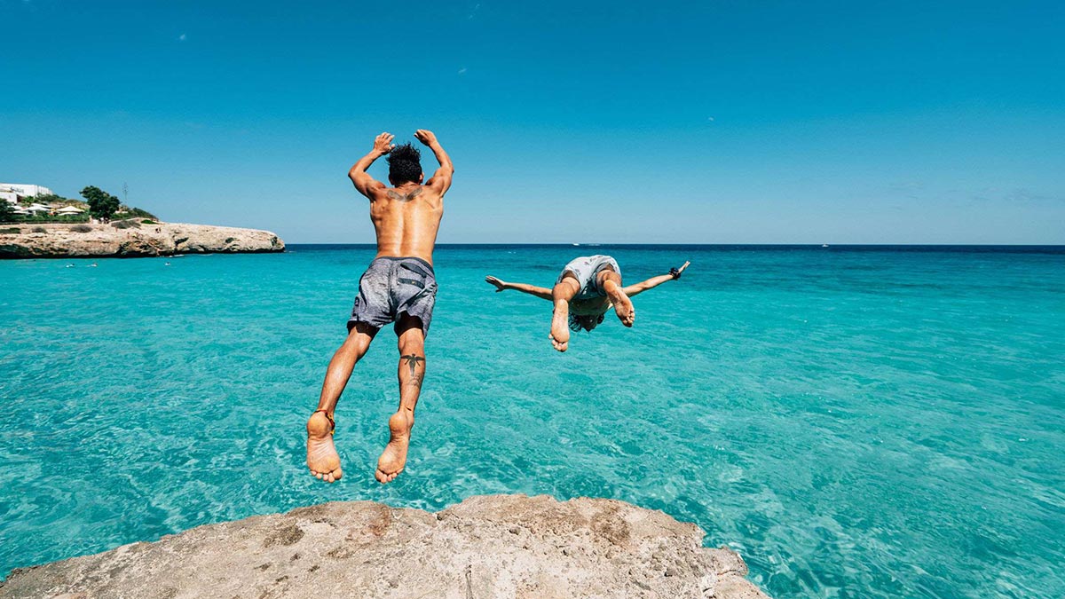Two people jumping into the sea in Palma.