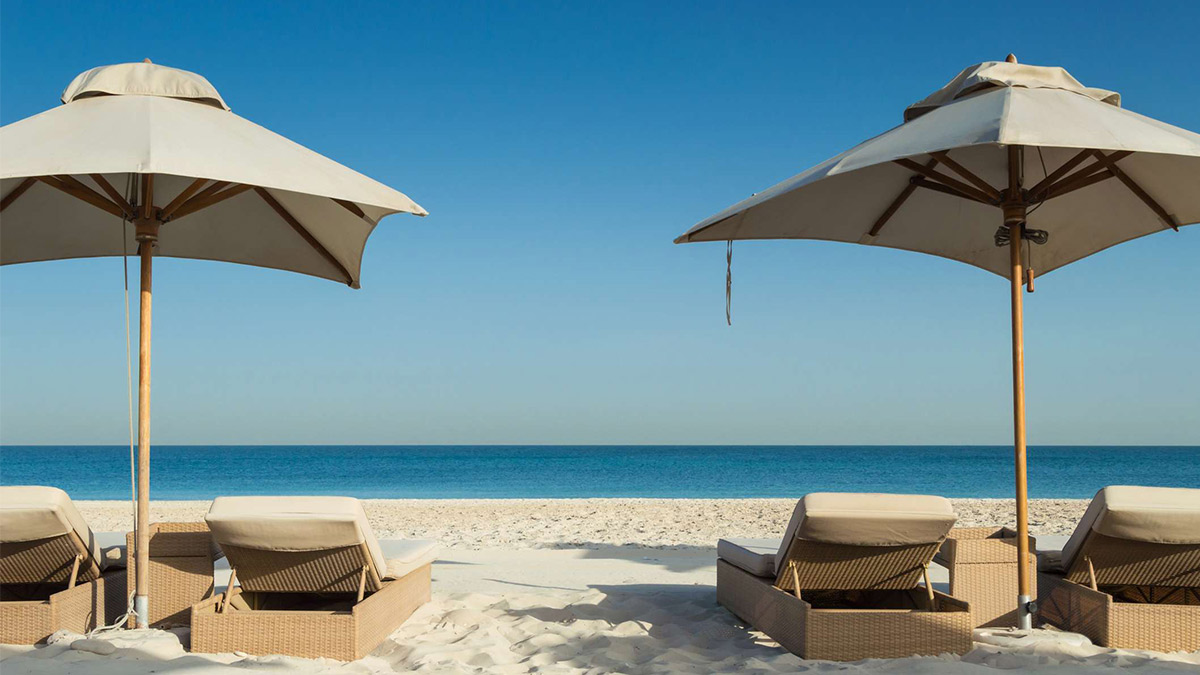 Beach umbrellas at a beautiful white beach in Abu Dhabi, in the UAE.