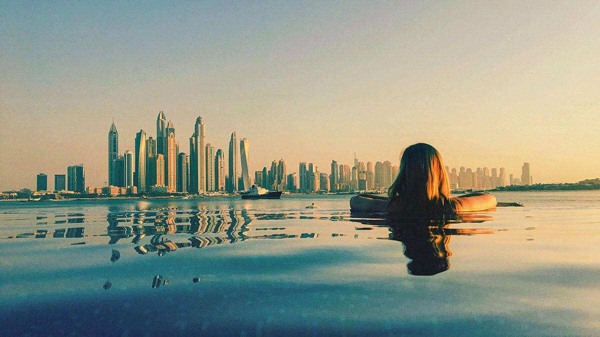 Woman watching over Dubai from swimming pool.
