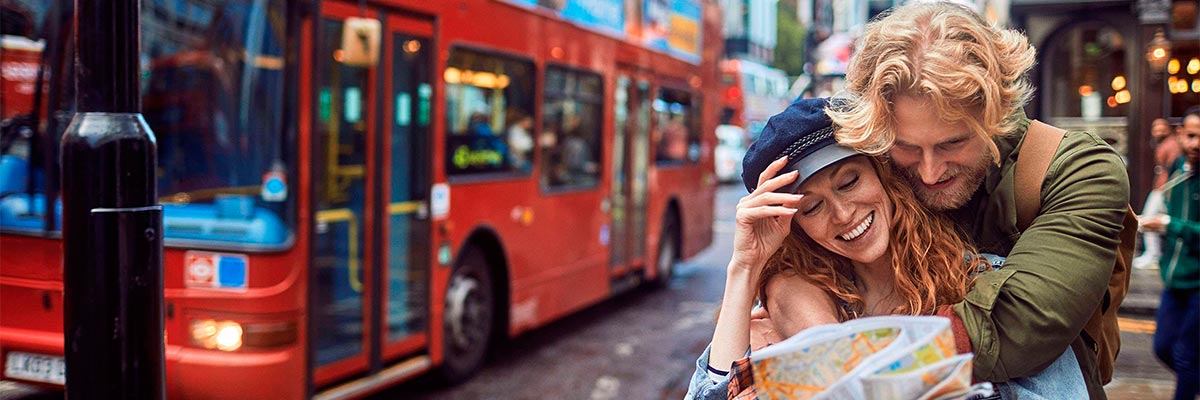 Paar erkundet London mit einem roten Bus im Hintergrund.