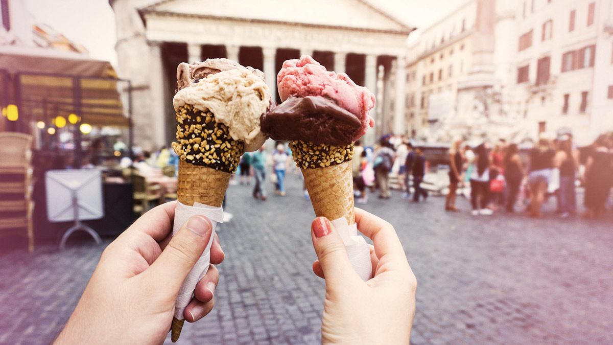 Two hands holding up ice cream cones.