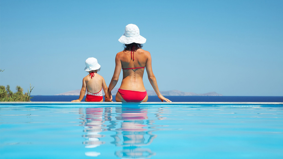 Woman and child stood in swimming pool.
