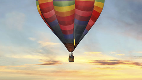 Balão de ar quente num céu colorido ao amanhecer.