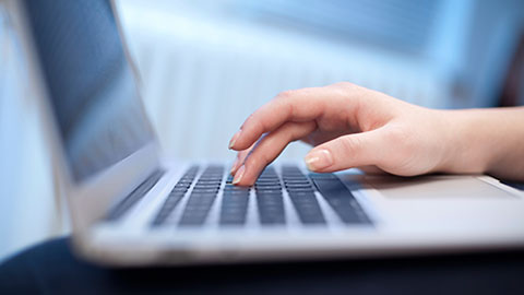 Mains tapant sur un clavier d'ordinateur portable.