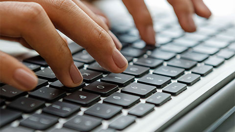 Gros plan d'une main tapant sur un clavier.