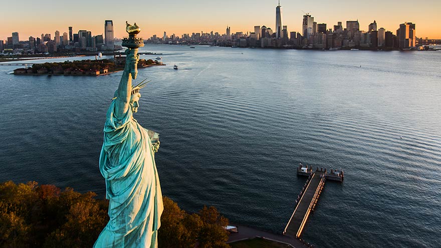 Aerial view of Statue of Liberty at sunrise. © Tetra Images.