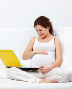 ラップトップコンピュータを持つ妊婦。